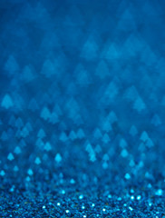 Blue holiday glitter background with Christmas tree bokeh.