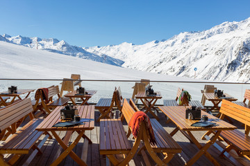 Chairs and Tables on an empty terrace at a ski cafe in an Austrian Resort with Snow capped...