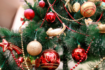 New Year colorful decoration ornaments on Christmas tree. Room decorated to christmas celebration, holiday scene with various shapes, multicolored balls, decorative sparkle bows and bird on tree.