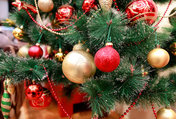 Naklejka na ściany i meble New Year colorful decoration ornaments on Christmas tree. Room decorated to christmas celebration, holiday scene with various shapes, multicolored balls, decorative sparkle bows and bird on tree.