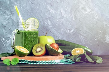 healthy green smoothie with ingredients on a wooden table: apple, kiwi, lime, spinach, mint, avocado, cucumber - 305420523
