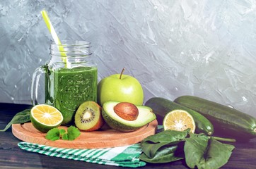 healthy green smoothie with ingredients on a wooden table: apple, kiwi, lime, spinach, mint, avocado, cucumber - 305420536