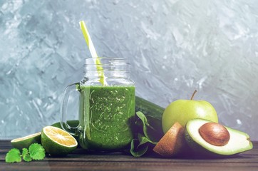 healthy green smoothie with ingredients on a wooden table: apple, kiwi, lime, spinach, mint, avocado, cucumber - 305420551