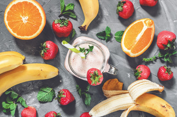 banana, strawberry and orange smoothies with mint in a glass with a straw on the table, top view - 305420983