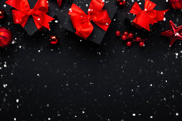 Merry Christmas and Happy Holidays greeting card, banner. New Year. Noel. Christmas red ornaments and gifts on black background top view. Winter xmas holiday theme.