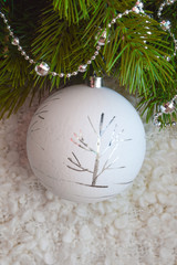 Decor for a happy Christmas and New year. Silver color. Christmas balls and beads on a white cozy blanket. happy winter holidays. Background for congratulations. White balls for Christmas tree decorat