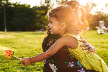 Mother having fun with her little daughter outdoors in nature green park.