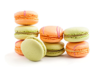 Orange and green macarons or macaroons cakes isolated on white background, side view.