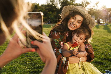 Fototapeta premium Someone take photo by mobile phone of woman and little daughter