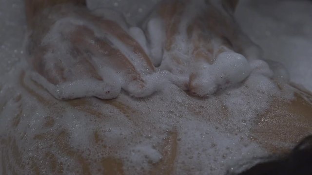  A woman lies in a Turkish bath-in a Hamam on a huge table on her stomach, a man massaging her back with the foams
