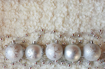 Decor for a happy Christmas and New year. Silver color. Christmas balls and beads on a white cozy blanket. happy winter holidays. Background for congratulations. Grey balls for Christmas tree decorati
