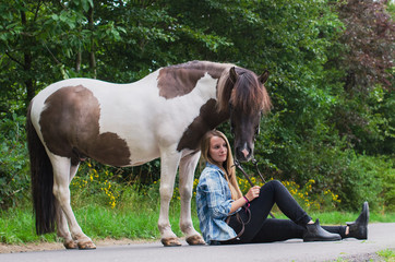 Reiterin sitzt auf einer Straße vor den Hufen ihres Ponys