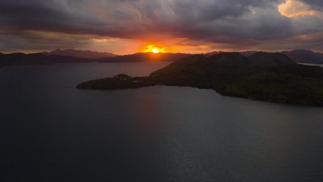 Aerial Hyper lapse of beautiful sunset with the sun setting behind the mountains at sea. The shot is reversible into a sunrise