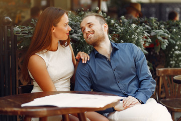 Cute couple in a city. Lady in a white dress. Pair sitting on a cafe