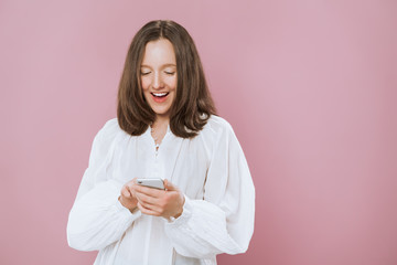 Image of a happy young beautiful woman posing copy space isolated over pink wall background using mobile phone.