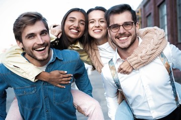 Two happy couple having fun piggyback ride outdoor, smiling happy, laughing together