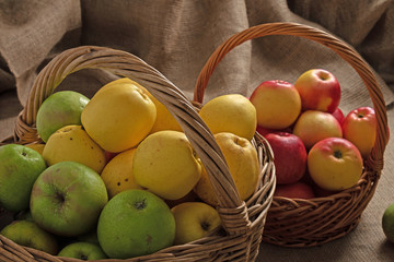 two baskets with different varieties of apples on a burlap background