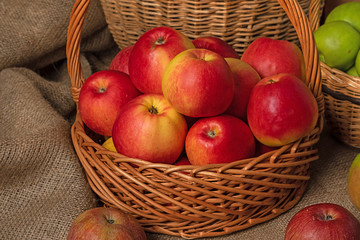 basket with red apples stands on burlap on the background of other baskets