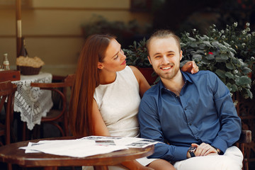 Cute couple in a city. Lady in a white dress. Pair sitting on a cafe