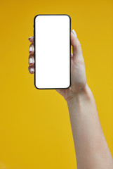 Fototapeta na wymiar Woman hands holding smartphone on a yellow background. Smartphone mockup with white screen