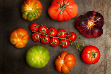 Variedad de tomates sobre tabla oscura insaturada. Vista superior