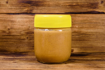 Glass jar with peanut butter on a wooden table