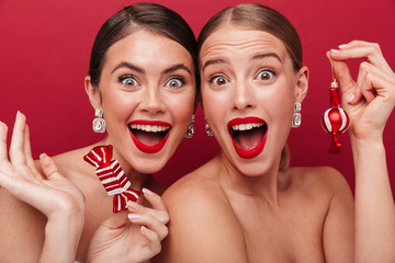 Positive women with bright red lipstick holding christmas tree toys.