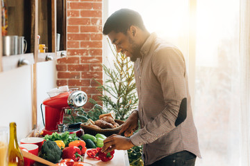 African-american man cutting bell pepper in kitchen