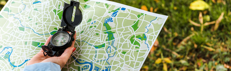 panoramic shot of woman holding map and vintage compass outside