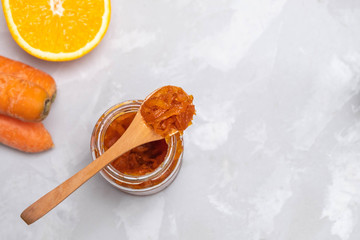 Fototapeta premium Jar of carrot jam made of sugar, carrots and oranges on concrete kitchen table
