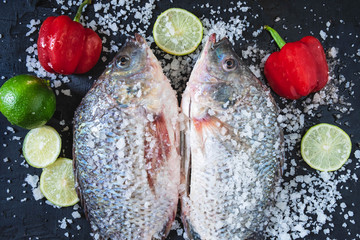 Fresh fish of tilapia with salt and seasoning for cooking.