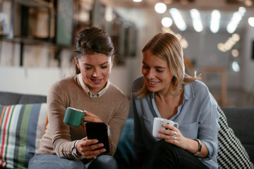 Best friends. Two beautiful woman sitting on sofa. Sisters at home