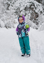 A child in the winter forest throws snow and laughs