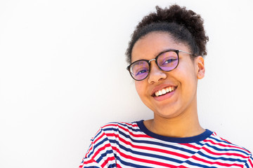 Close up of smiling young african american girl with glasses by white wall