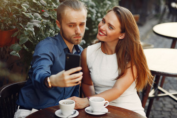 Male wih a phone. Man make a selfie. Lady in a white dress. Pair sitting on a cafe