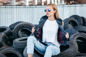 Fototapeta na wymiar Girl wearing t-shirt, glasses and leather jacket posing against street , urban clothing style. Street photography