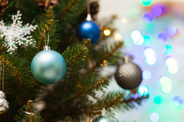 Beautiful green Christmas tree decorated with blue balls and garlands. Close-up photo. Sparkling background