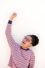 cute smiling african american teenage girl with glasses and arm raised by white background