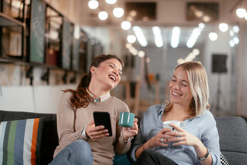 Best friends. Two beautiful woman sitting on sofa. Sisters at home