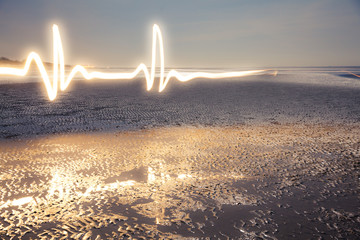 Light Painting Art: Luminous lifeline painted with a flashlight at the blue hour on the beach at...