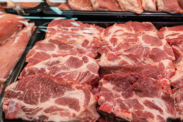 Selection of quality meat at a butcher shop, butchered pork in a refrigerated display case under...