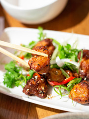Chopsticks Pick Up Japanese Karaage Chicken from a White Plate. Authentic Shot from Restaurant.