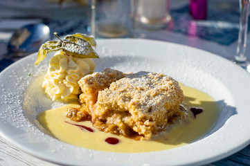 Rhubarb Crumble with Cream and White Sauce in a Plate. Authentic Shot from Restaurant.