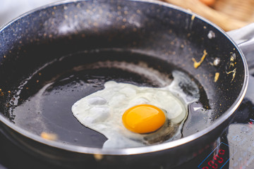 yellow yolk egg, fried egg cooking on flying pan in oil on electric stove, close up selective focus, with copy space