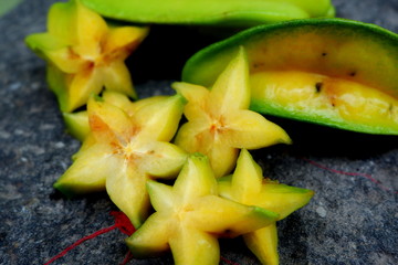 Close up of fruit star (Averrhoa carambola) on the black stone. Top view close up details.