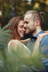 Cute couple in a park. Lady in a white dress. Man in a blue shirt