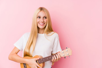 Fototapeta premium Young blonde girl playing ukelele smiling confident with crossed arms.