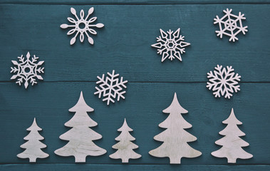 The christmas composition with wooden snowflakes above the wooden trees on the dark wooden table