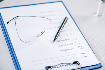 selective focus of pen near glasses and clipboard with checklist in clinic