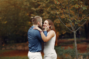 Fototapeta premium Cute couple in a park. Lady in a white dress. Man in a blue shirt